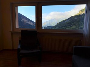 Ein Zimmer mit zwei Fenstern mit Blick auf eine gebirgige Landschaft.