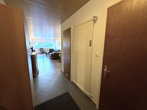 Ein Flur, der in einen Raum mit Tür und Fenster sowie Blick ins Freie führt.