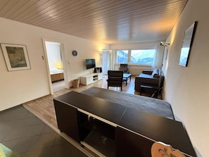 Un salon moderne avec un téléviseur  à écran plat, un canapé et un coin repas.
