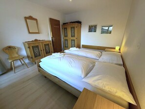 A bedroom with a double bed, wooden wardrobe, and a chair. - Salve 9 # 6-bed apartment, Dusche, WC 6-Bettwohnung, Dusche, WC by Interhome (Leukerbad)