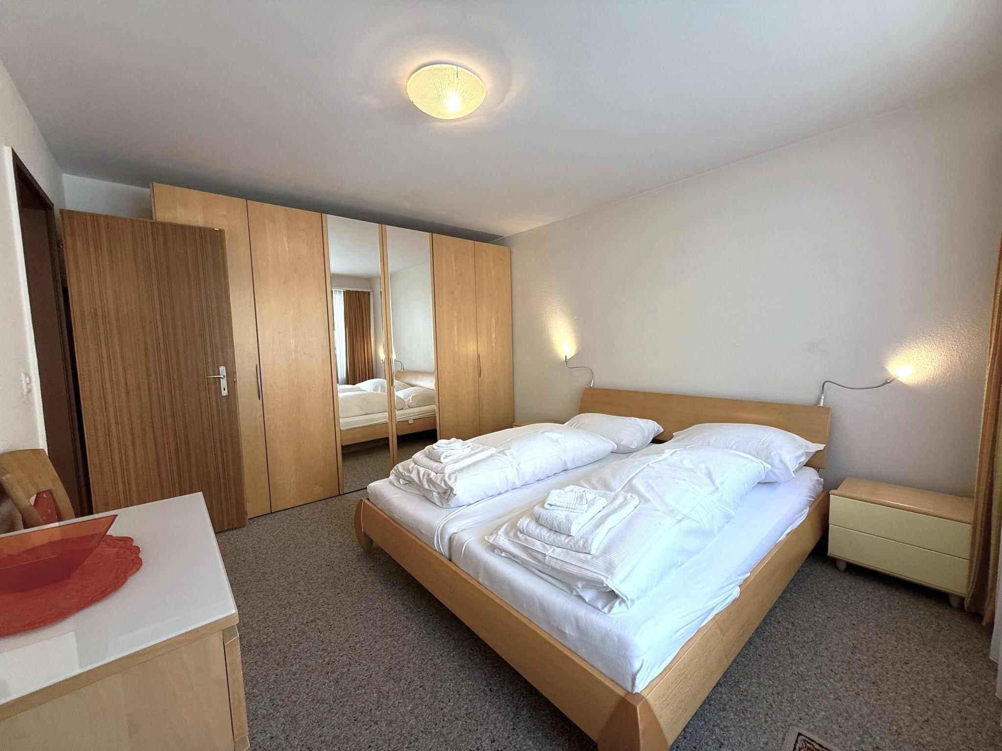 Una camera d'albergo con un letto grande, un'armadietto di legno, una scrivania e uno specchio.