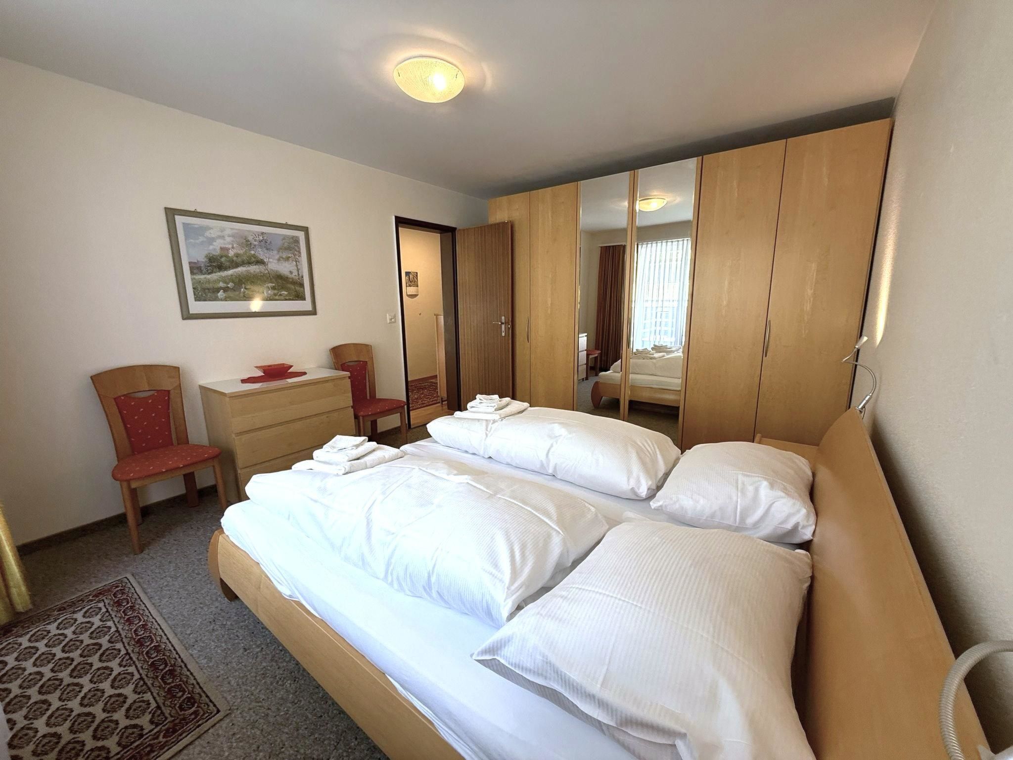 Ein Hotelzimmer mit Bett, Schreibtisch, Stuhl, Kleiderschrank und einem Bild an der Wand.
