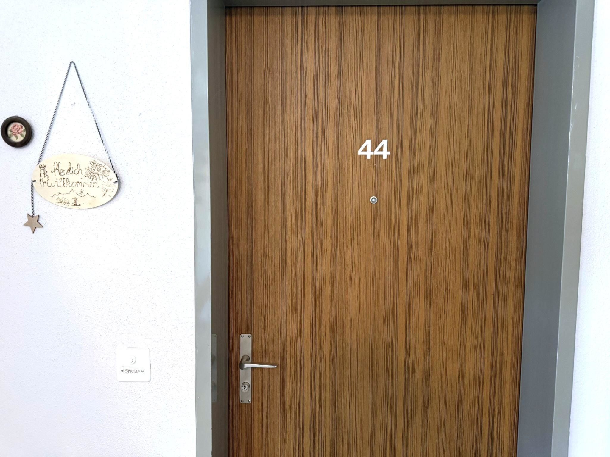 A wooden door with the number 44, a door handle, and a welcome sign with a star.