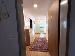 Ein Flur mit Holzboden, einem gemusterten Teppich und einer Tür zu einem Zimmer.