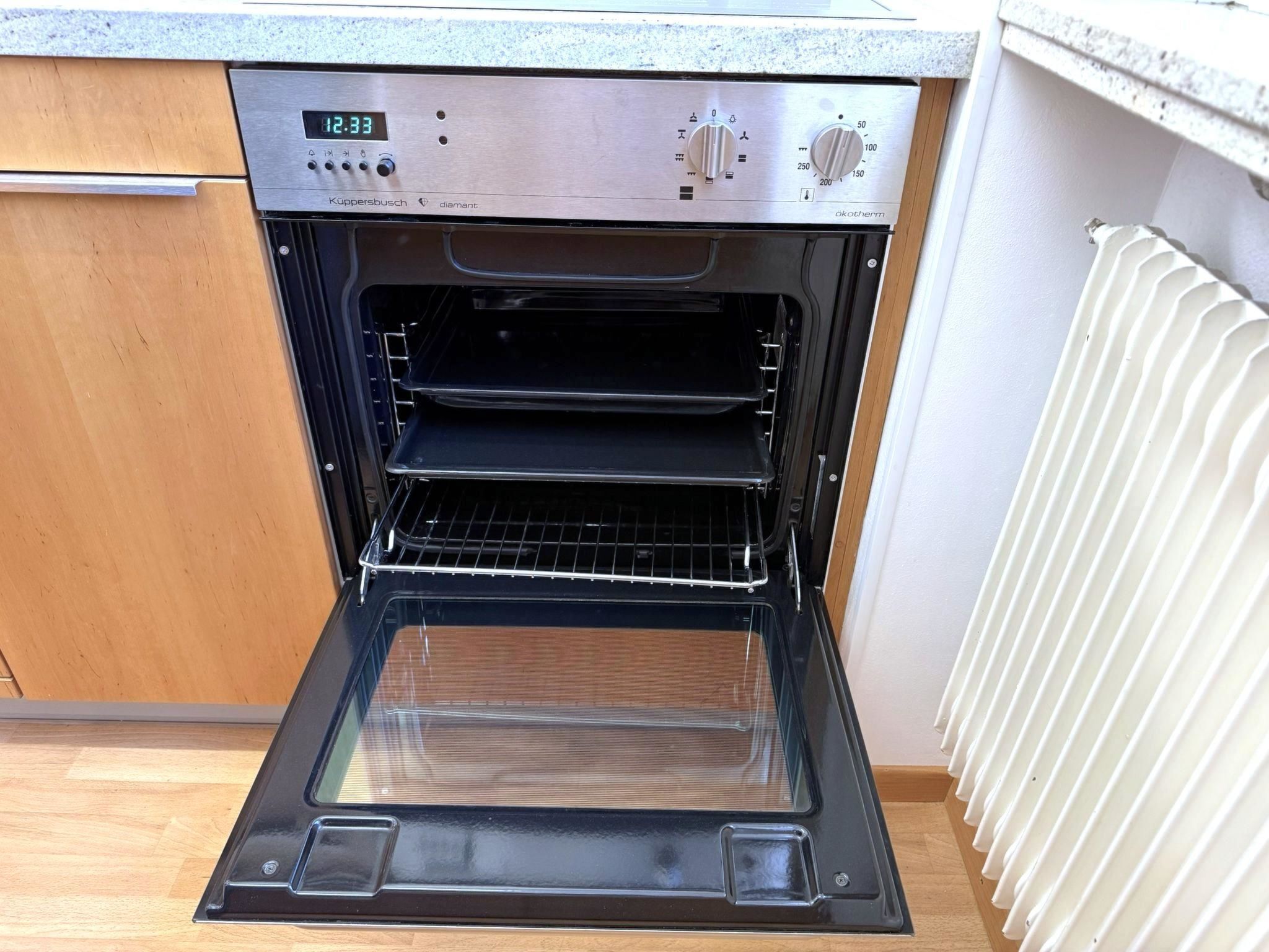 Une cuisine ouverte avec un four encastré, un écran numérique et un bouton de commande.