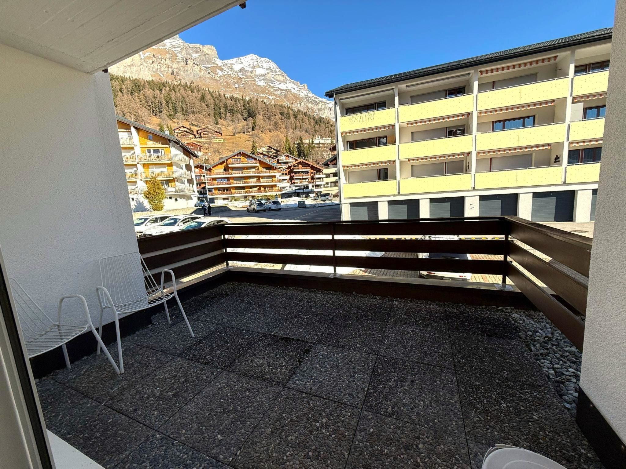 Un balcon avec vue sur une montagne et un parking.