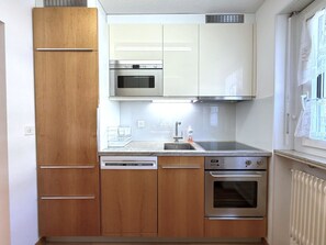 Eine kompakte Küche mit Geschirrspüler, Backofen, Mikrowelle und einem Fenster mit Blick.