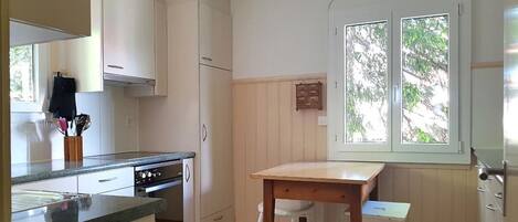 A compact kitchen with a stove, oven, and a small dining table with two chairs.