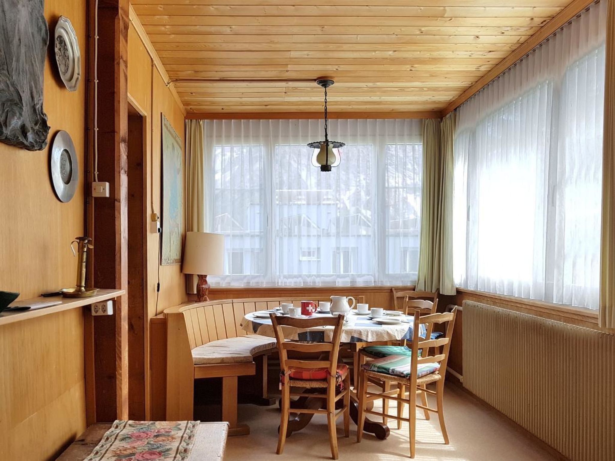 Un comedor acogedor con una mesa de madera, sillas y una lámpara colgante.