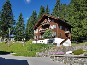 A multi-story chalet with balconies, set in a mountainous area with lush greenery and pine trees. - Chalet Willi-1.OG Appartement/Fewo, Dusche und Bad, WC, 9-Bettwohnung by Interhome (Arosa)