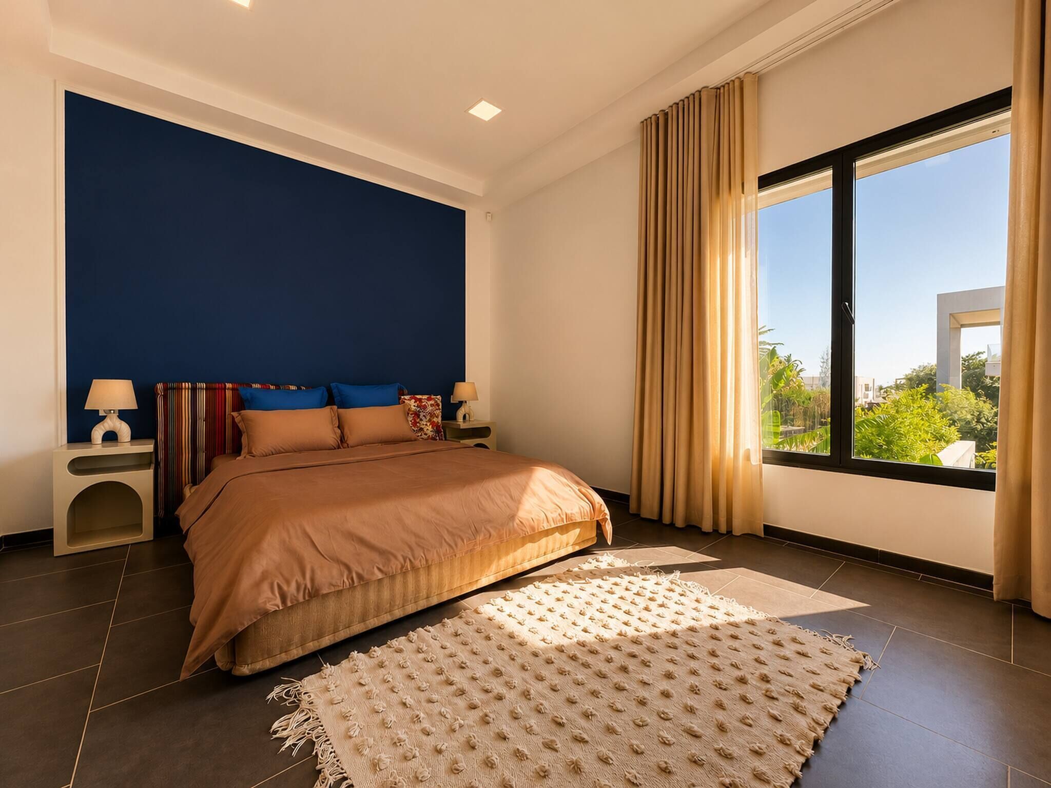 Een moderne slaapkamer met een groot bed, twee nachtkastjes, een raam met gordijnen en uitzicht op groen.