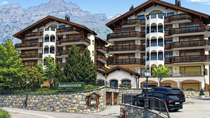 A multi-story hotel with balconies, a stone facade, and a mountain backdrop. - Ambassador Leukerbad # 4-bed apartment, Dusche und Bad, WC by Interhome (Leukerbad)