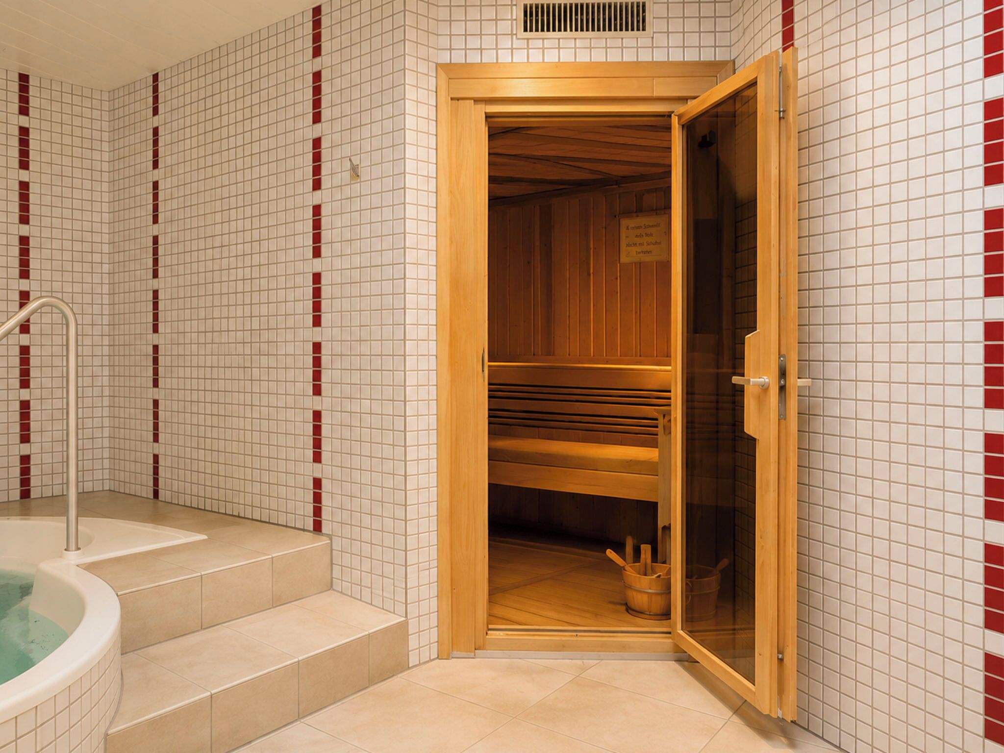A sauna room with a wooden bench, a glass door, and a tiled floor.