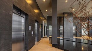 A modern elevator area with metallic elevators, a trash bin, and a geometric light fixture. - Film studio with parking space - 800 m from the park. Ibirapuera (São Paulo)