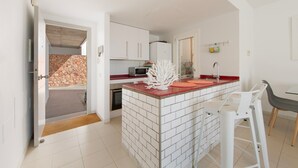 A modern kitchen with white cabinetry, a red countertop, and a central island with stools.