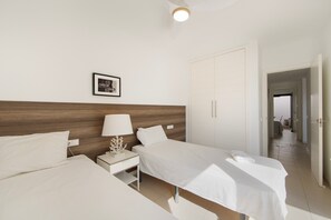 Habitación de hotel con dos camas, una mesita de noche, una lámpara, un cuadro enmarcado y un armario.