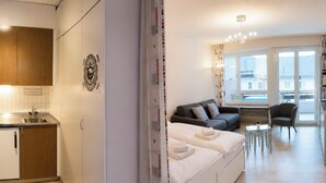 Eine moderne Wohnung mit einer Küchenzeile, einer Schlafcouch, einem Essbereich und großen Fenstern.