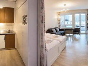 Eine moderne Wohnung mit einer Küchenzeile, einer Schlafcouch, einem Essbereich und großen Fenstern.