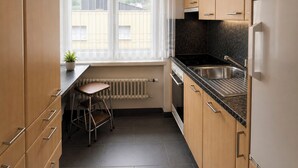 Eine moderne Küche mit Holdekor-Schränken, einer schwarzen Arbeitsplatte, einer Edelstahl-Spüle und einem eingebauten Backofen.