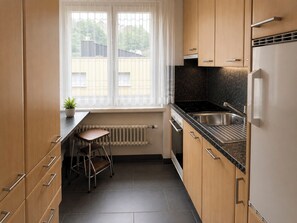 Eine moderne Küche mit Holdekor-Schränken, einer schwarzen Arbeitsplatte, einer Edelstahl-Spüle und einem eingebauten Backofen.