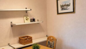 Ein Essbereich mit Holztisch, zwei Stühlen, einer Hängeleuchte und einem gerahmten Bild an der Wand.