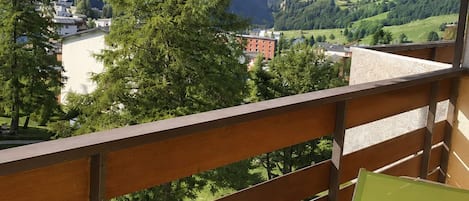 An outdoor dining area with a table set for two, overlooking a mountainous landscape.