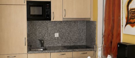 A compact kitchen with a microwave, a sink, and a small countertop.