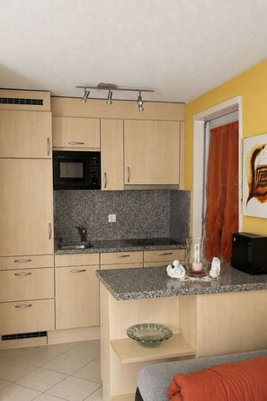 A compact kitchen with a microwave, a sink, and a small countertop. - Majesta Leukerbad # 4-bed apartment, Dusche, WC by Interhome (Leukerbad)