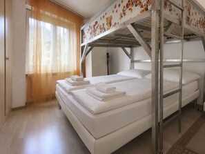 A bunk bed room with two beds, a window with sheer curtains, and a door. - Majesta Leukerbad # 4-bed apartment, Dusche, WC by Interhome (Leukerbad)