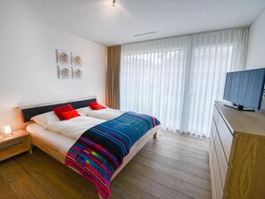 Ein Hotelzimmer mit Bett, Nachttisch, Fernseher und einem Fenster mit Vorhängen.