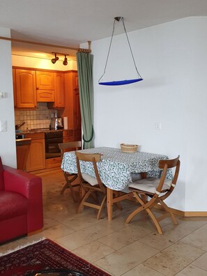 Ein Essbereich mit Tisch und Stühlen, eine rote Couch und eine Küche im Hintergrund.