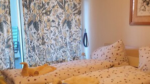 Ett hotellrum med en säng, ett fönster med gardiner och en telefon som är monterad på väggen.