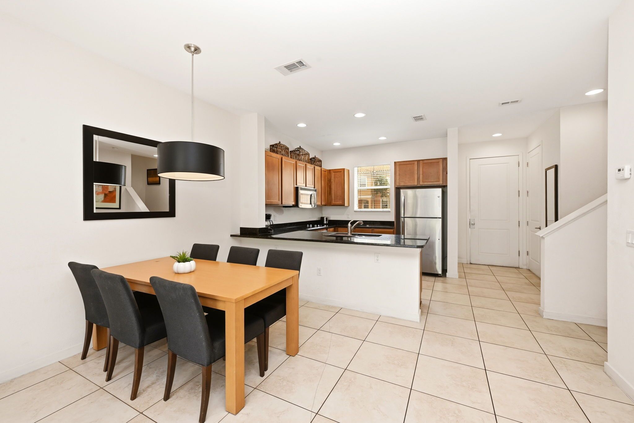 A modern kitchen with a central island, wooden cabinets, and a dining area with a table and chairs.