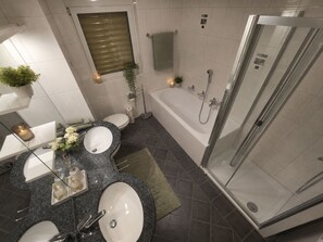 Une salle de bain moderne avec deux lavabos, une baignoire et une douche à parois de verre.