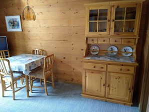 A wooden interior with a dining table, chairs, a hanging light fixture, and a kitchen area with cabinets and a countertop. - Gassenboden 32 # 2-bed apartment, Dusche, WC 2-Bettwohnung, Dusche, WC by Interhome (Leukerbad)