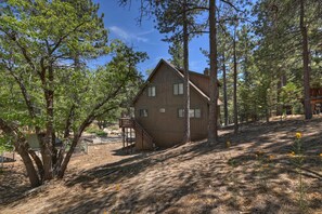 A wooden cabin with a staircase leading to a deck, surrounded by trees and a clear sky. - Natures Peak-family Retreat w/ 2 Fireplaces (Green Valley Lake)