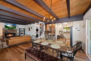A spacious living area with a fireplace, a dining table set for four, and a kitchen in the background. - Natures Peak-family Retreat w/ 2 Fireplaces (Green Valley Lake)