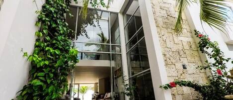 A modern building with large glass windows, a stone facade, and a courtyard with seating.