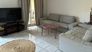 A living room with a television, sofa, and a small table. - House with a garden in Candillargues (Candillargues)