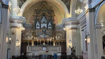En kyrkinteriör med bänkar, en stor orgel och utsmyckade takdekorationer.