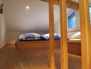 Ein kleines Zimmer mit einem Einzelbett, schrägem Dach und einem Fenster.