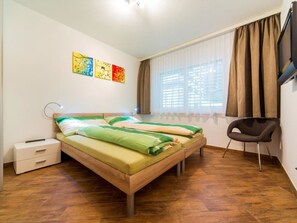 Ein Schlafzimmer mit einem Bett, einem Sessel, einem Nachttisch und Bildern an der Wand.
