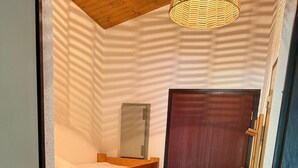 Ein schmales Zimmer mit Etagenbetten, einer Holztür und einem kleinen Heizgerät an der Wand.