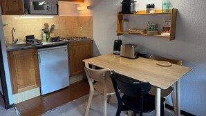 Eine kleine Küche mit Holzausstattung, einer Mikrowelle, einer Kaffeemaschine und einem Toaster auf einem Holztisch.