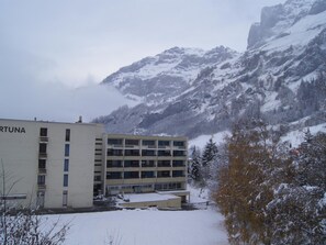 Ein Gebäude mit der Aufschrift 'FORTUNA' an der Fassade, umgeben von schneebedeckten Bergen und Bäumen.