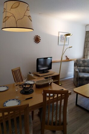 A living room with a television, dining table, chairs, and a sofa. - Fortuna 404 # 3-bed apartment, Dusche, WC 3-Bettwohnung, Dusche, WC by Interhome (Leukerbad)