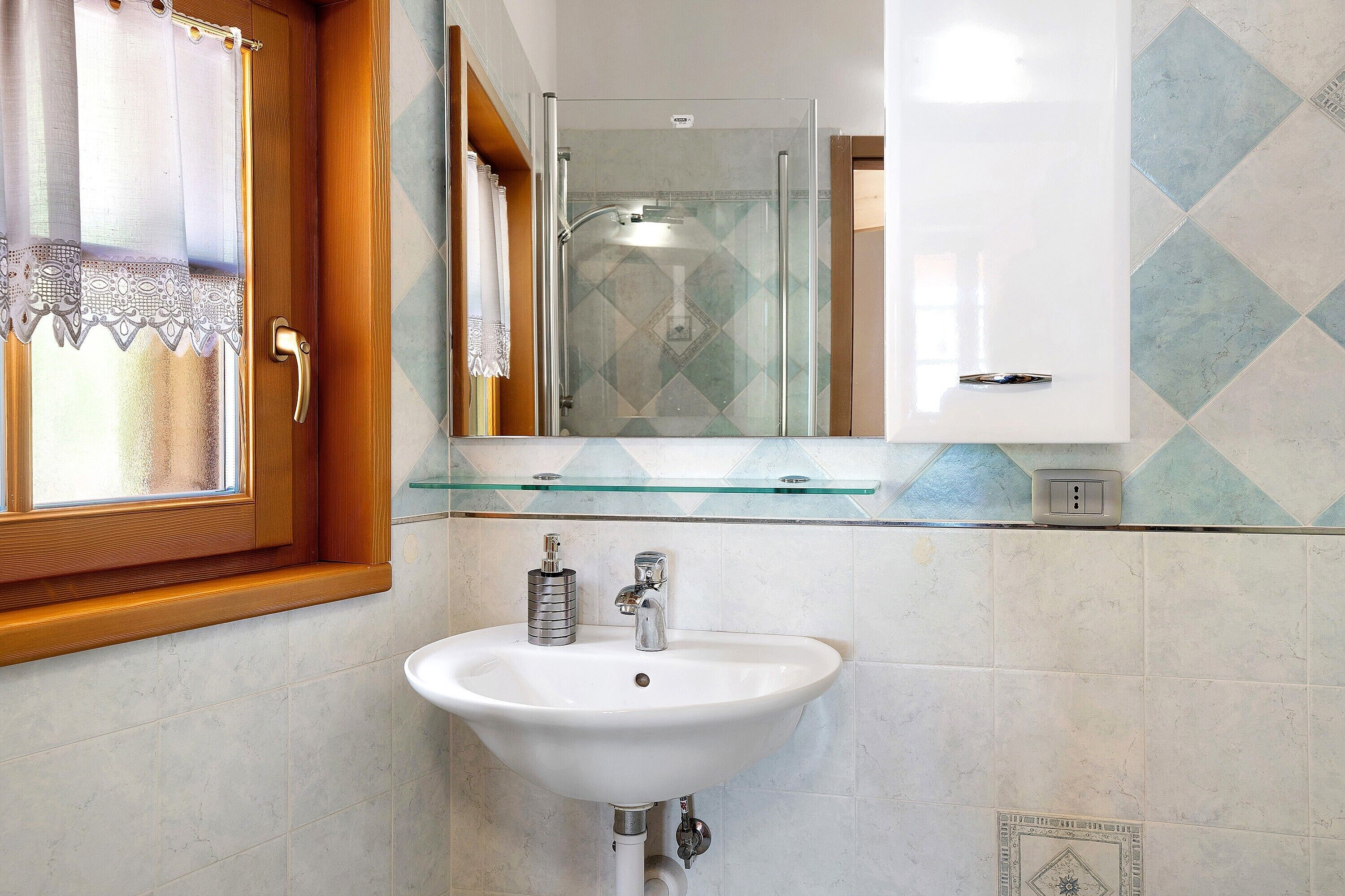 A bathroom with a white sink, a glass shower enclosure, and a mirror above the sink.