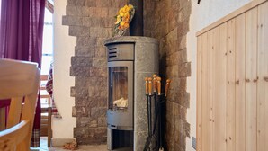A stone fireplace with a flower arrangement, a wooden door, and a hearth with tools.