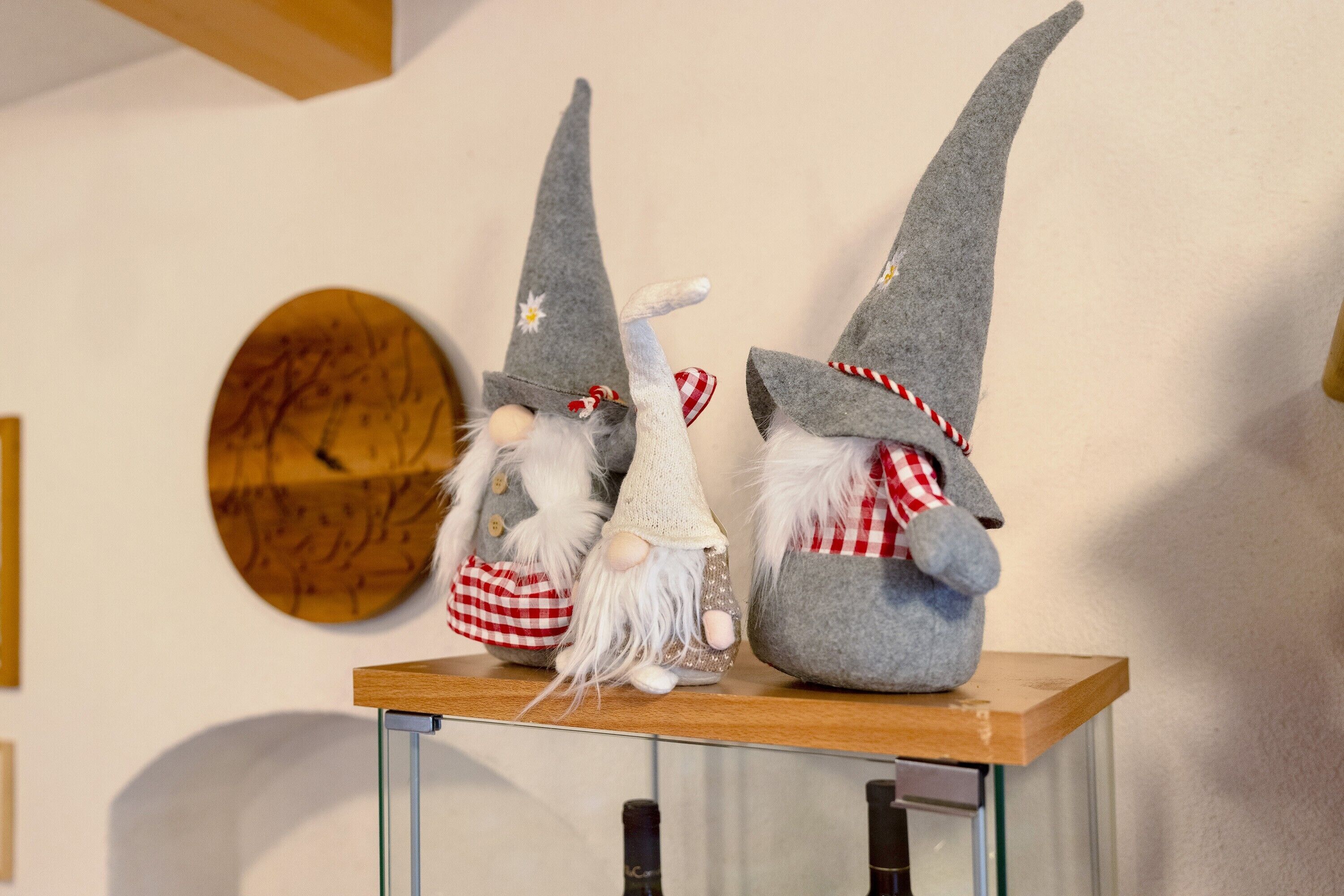 Three gnome figurines on a wooden shelf.