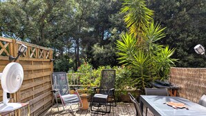 Een houten terras met buitenmeubilair, een ventilator en een tafel.